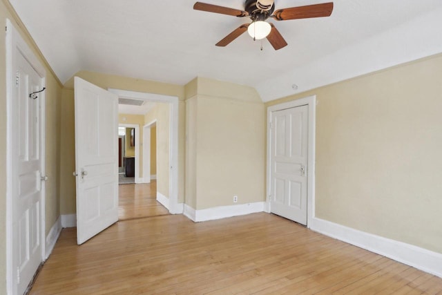 empty room with ceiling fan, light wood-type flooring, and vaulted ceiling