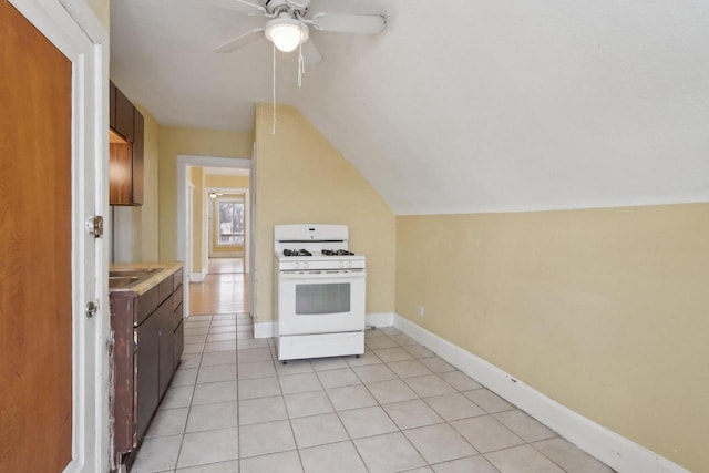 kitchen featuring lofted ceiling, ceiling fan, light tile patterned floors, sink, and white gas range oven