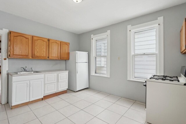 kitchen with white appliances, light tile patterned floors, and sink