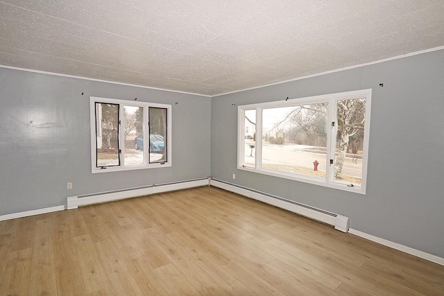 unfurnished room featuring baseboard heating, ornamental molding, and light hardwood / wood-style floors