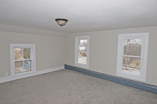 carpeted empty room with a baseboard radiator, vaulted ceiling, and a textured ceiling