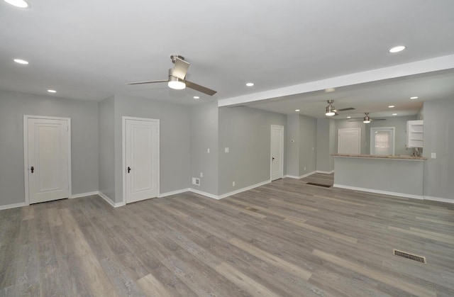 unfurnished living room featuring ceiling fan and light hardwood / wood-style flooring