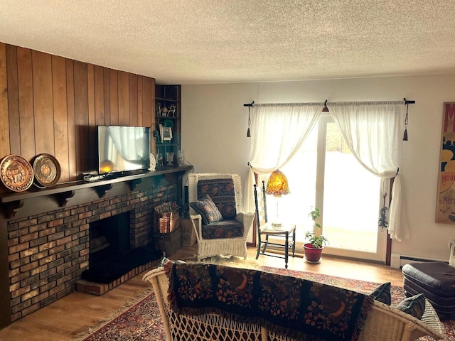 living room featuring hardwood / wood-style flooring, a brick fireplace, and a textured ceiling