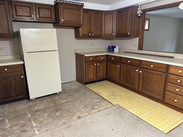 kitchen with white fridge and dark brown cabinetry