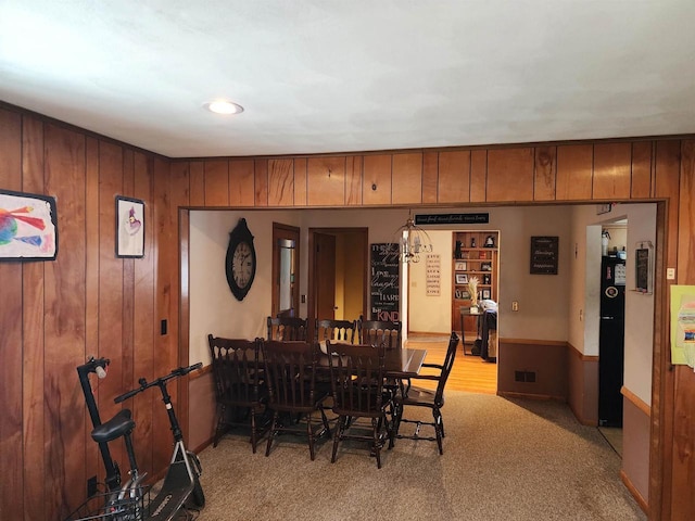 carpeted dining room featuring wood walls