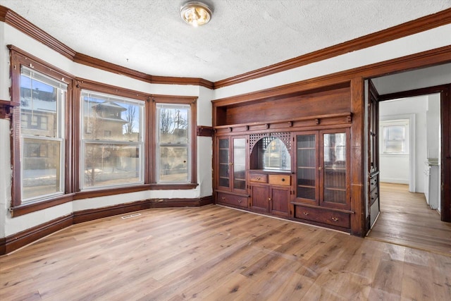 unfurnished living room featuring light hardwood / wood-style floors, crown molding, and a textured ceiling