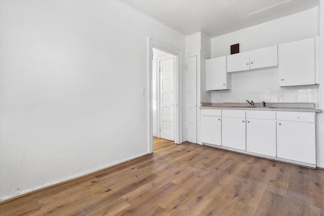 kitchen featuring white cabinetry, sink, and light hardwood / wood-style flooring