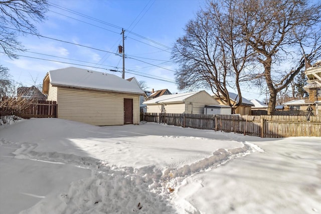 yard layered in snow with a garage and an outdoor structure