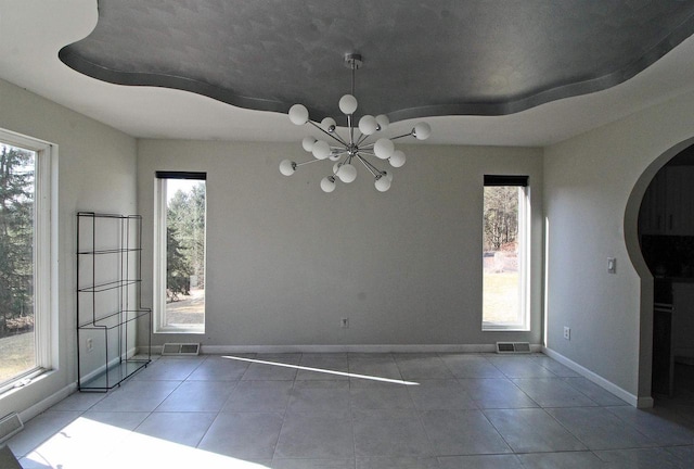 unfurnished dining area with a wealth of natural light, baseboards, arched walkways, and an inviting chandelier