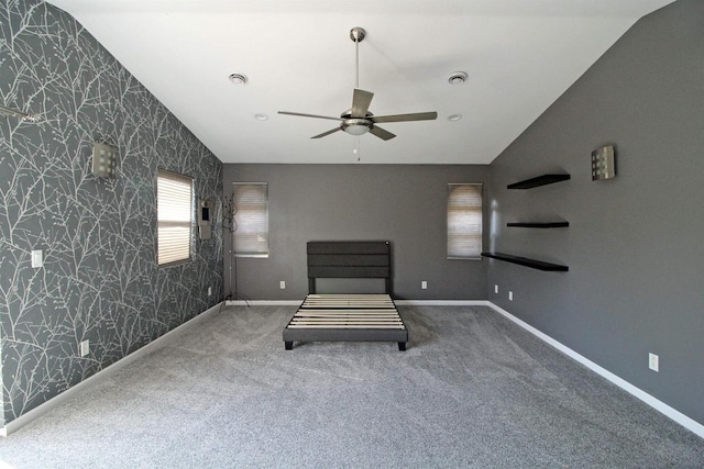 unfurnished bedroom with wallpapered walls, vaulted ceiling, and carpet