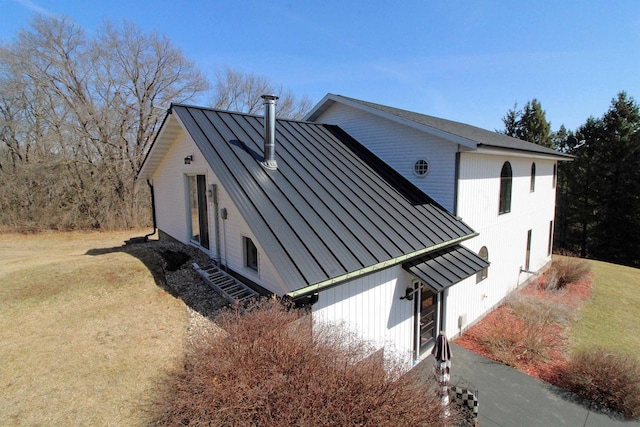 view of home's exterior with a standing seam roof, a yard, and metal roof