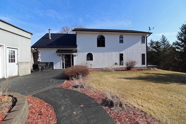 rear view of house featuring metal roof and a yard