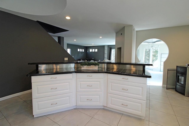 kitchen with stove, white cabinets, light tile patterned flooring, and recessed lighting