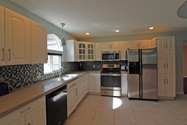 kitchen with hanging light fixtures, decorative backsplash, appliances with stainless steel finishes, and a sink