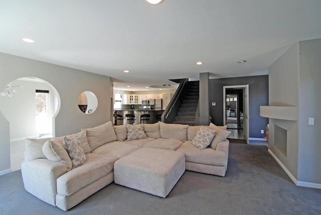 carpeted living room with recessed lighting, baseboards, and stairs