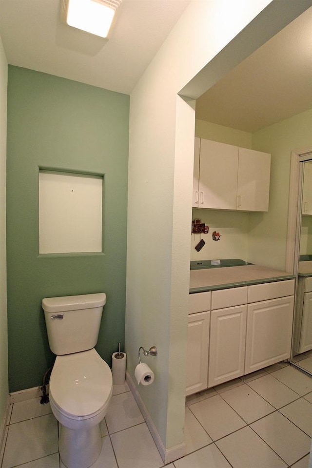 bathroom with tile patterned flooring, toilet, vanity, and baseboards