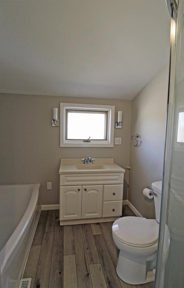 bathroom featuring vanity, toilet, wood finished floors, and baseboards