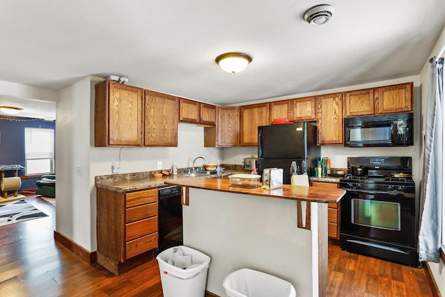 kitchen with dark hardwood / wood-style floors, a center island, sink, and black appliances