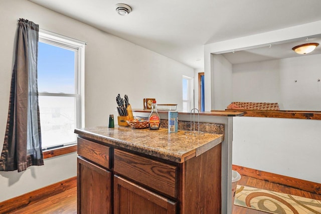 kitchen featuring a kitchen island, light stone counters, and light hardwood / wood-style floors