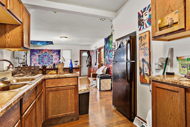 kitchen with black refrigerator, sink, and hardwood / wood-style floors