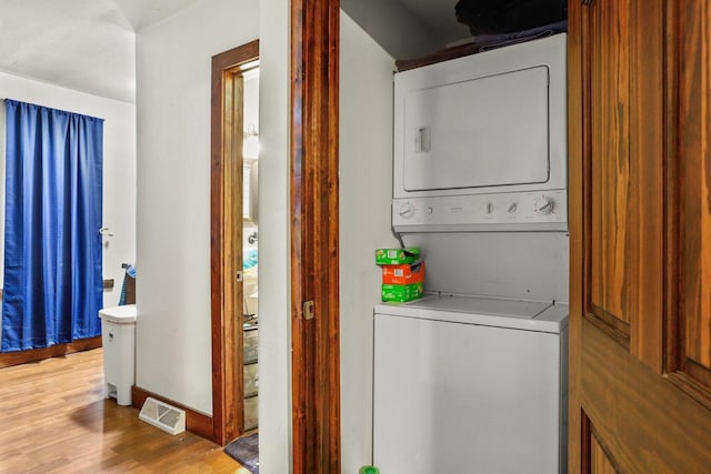 laundry area featuring stacked washer / dryer and light hardwood / wood-style floors