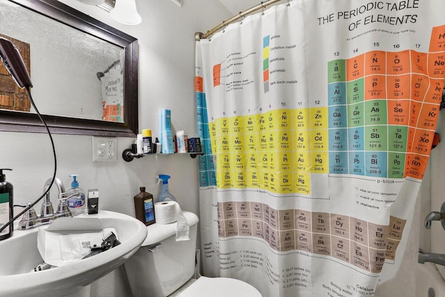 bathroom featuring a shower with curtain, toilet, and sink