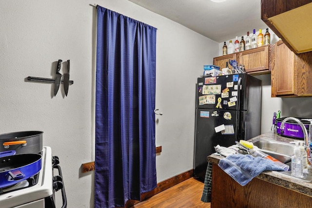 kitchen featuring dark hardwood / wood-style flooring, sink, and black fridge