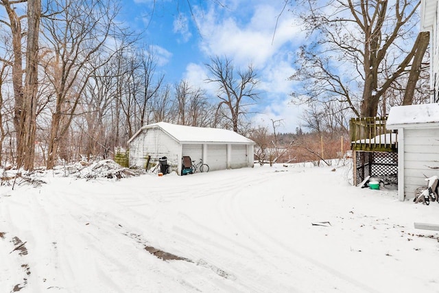 snowy yard with a garage and an outdoor structure