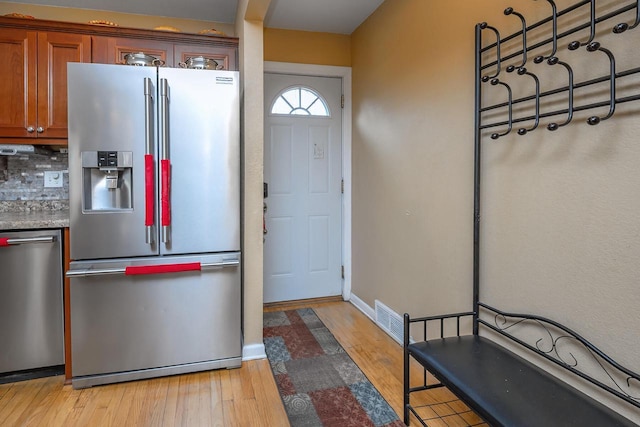 kitchen with tasteful backsplash, light hardwood / wood-style flooring, and appliances with stainless steel finishes