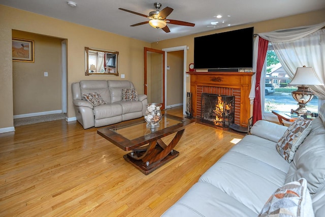 living room featuring hardwood / wood-style flooring, ceiling fan, and a fireplace