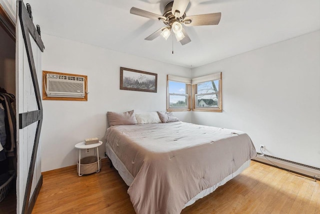 bedroom featuring a wall mounted air conditioner, a baseboard heating unit, hardwood / wood-style floors, and ceiling fan