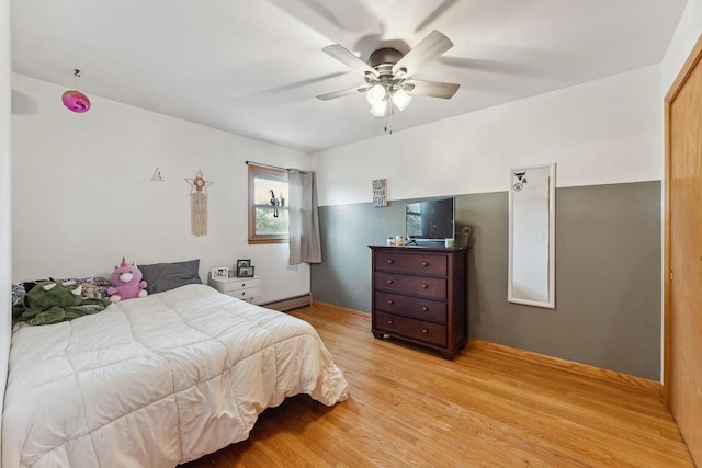 bedroom featuring ceiling fan, a baseboard radiator, and light wood-type flooring