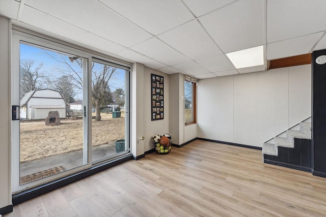 interior space featuring a paneled ceiling and light hardwood / wood-style floors