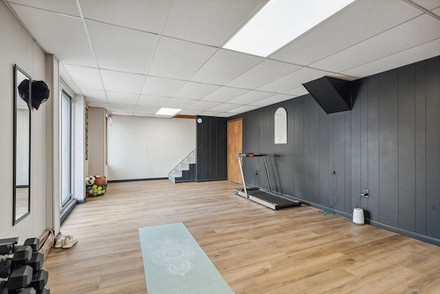 workout area featuring a drop ceiling and light hardwood / wood-style floors