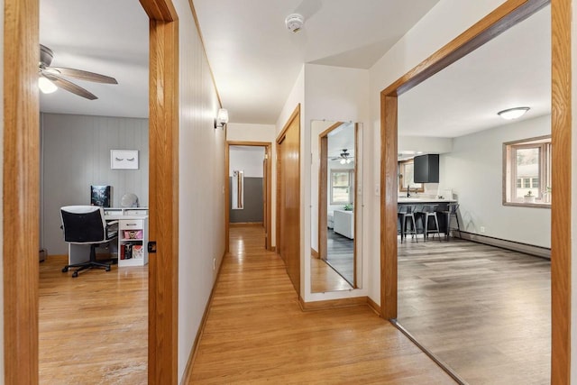 hallway with baseboard heating and light hardwood / wood-style flooring