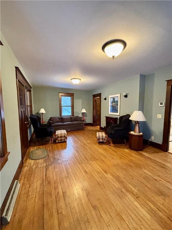 living room with a baseboard heating unit and light hardwood / wood-style floors