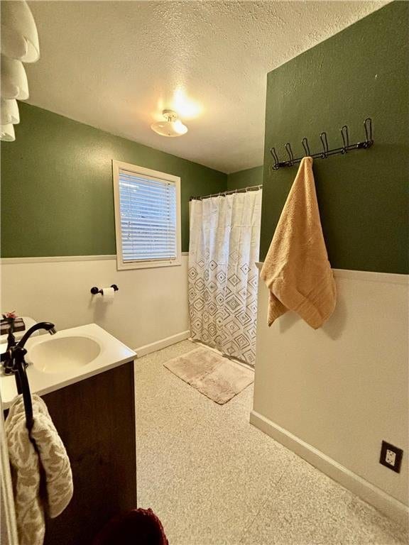 bathroom featuring vanity, curtained shower, and a textured ceiling