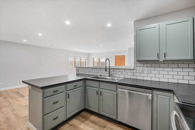 kitchen with sink, light hardwood / wood-style floors, stainless steel appliances, kitchen peninsula, and decorative backsplash