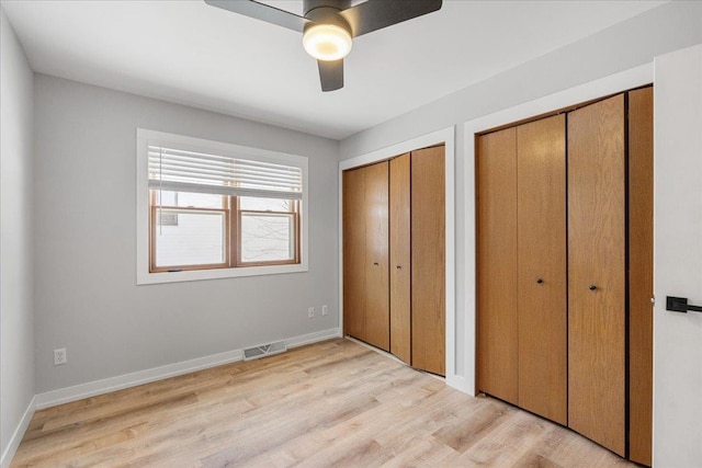 unfurnished bedroom featuring ceiling fan, two closets, and light hardwood / wood-style floors