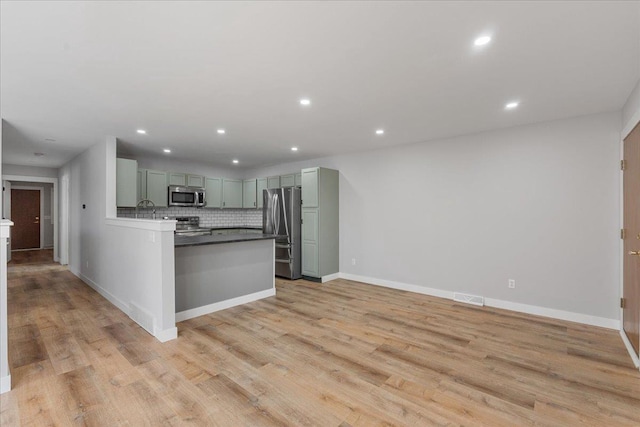 kitchen with sink, appliances with stainless steel finishes, tasteful backsplash, and light hardwood / wood-style flooring