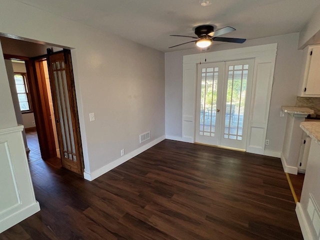 unfurnished dining area with dark wood-type flooring, a barn door, ceiling fan, and plenty of natural light