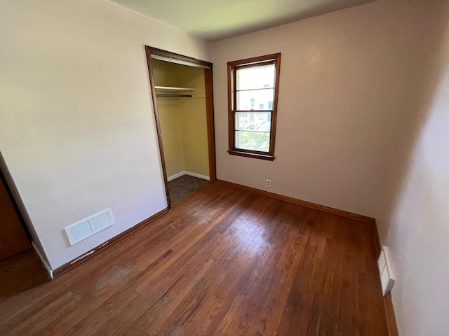 unfurnished bedroom with dark hardwood / wood-style floors and a closet