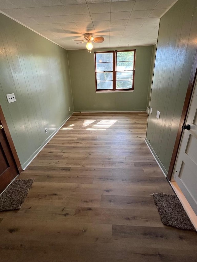 interior space featuring wooden walls, hardwood / wood-style floors, and ceiling fan