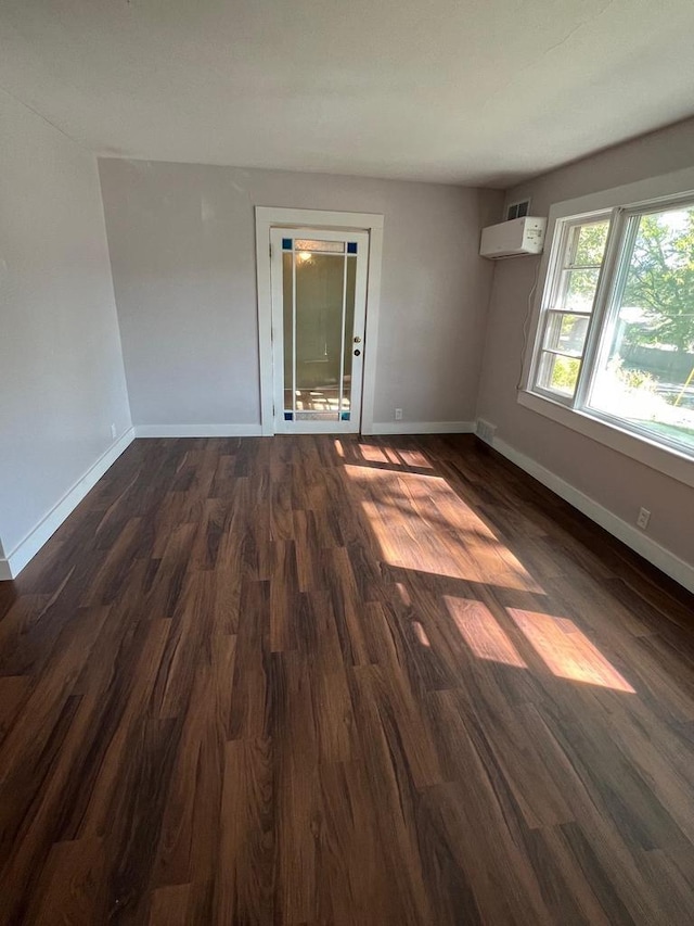 empty room with a wall mounted air conditioner and dark hardwood / wood-style flooring