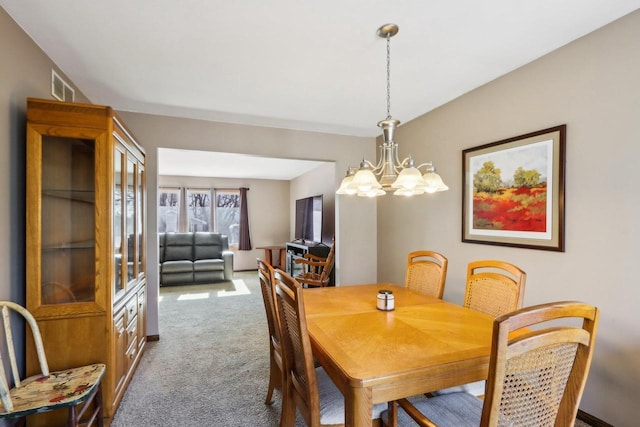 dining room with carpet and a notable chandelier