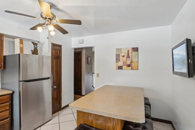 kitchen with stainless steel refrigerator, ceiling fan, kitchen peninsula, and light tile patterned floors