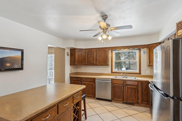 kitchen featuring tasteful backsplash, sink, light tile patterned floors, ceiling fan, and stainless steel appliances