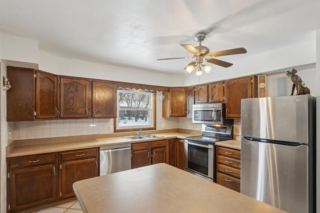 kitchen with light tile patterned flooring, tasteful backsplash, sink, ceiling fan, and stainless steel appliances