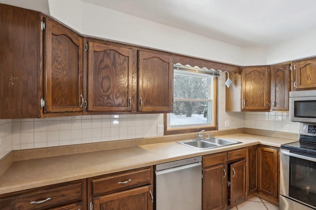 kitchen featuring tasteful backsplash, sink, light tile patterned floors, and stainless steel appliances