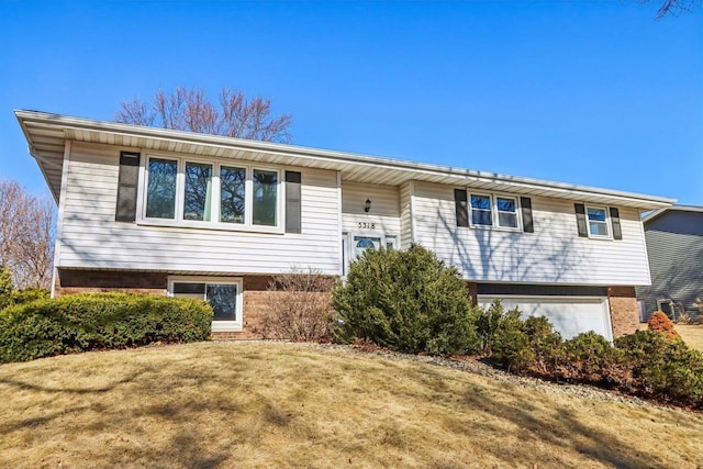 split foyer home with a garage and a front yard